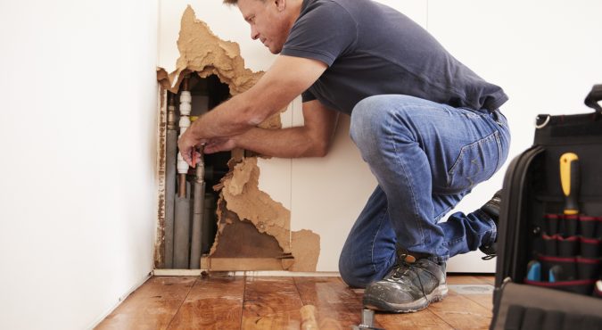 Middle aged man repairing burst water pipe