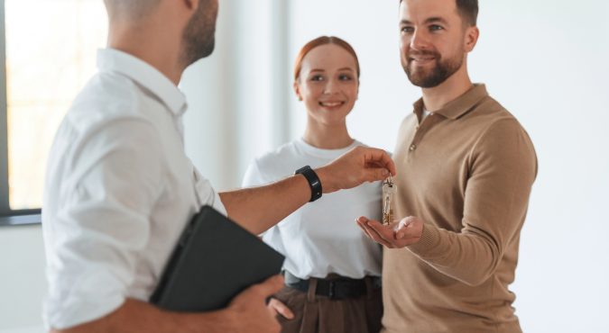 Customers bought the place, receiving the keys. Realtor shows an apartment to a young couple.